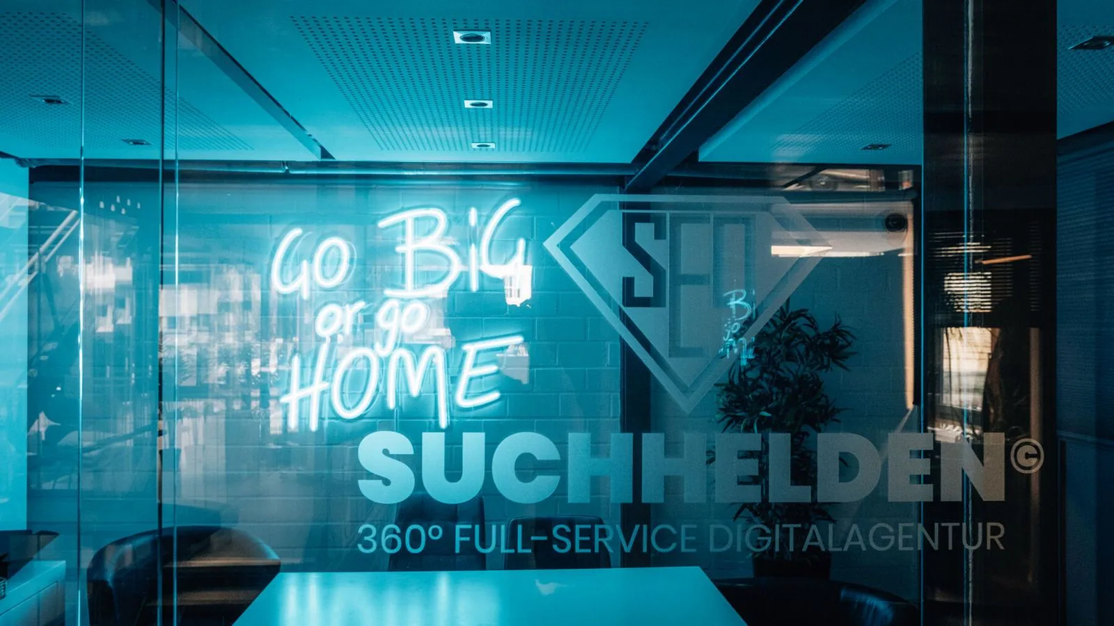 Glaswand mit „Go big or go home“ und Suchhelden-Schriftzug im Büro in Osnabrück