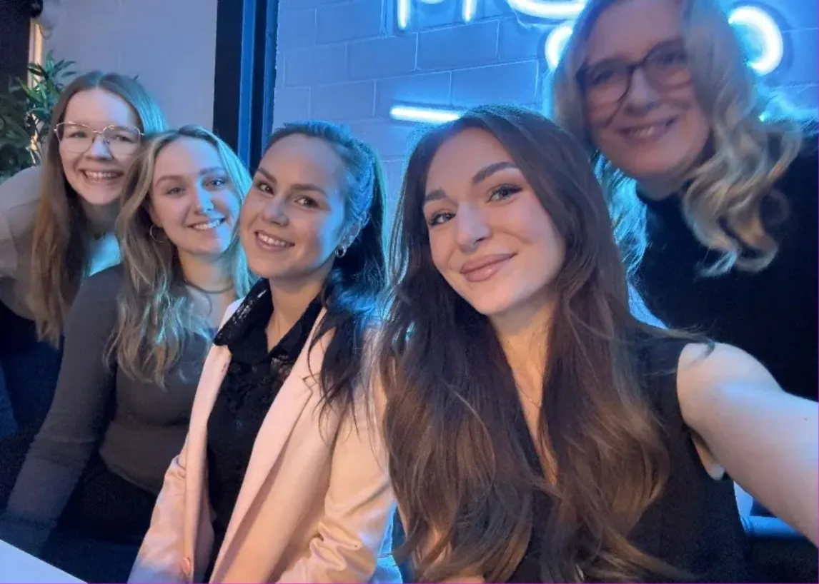 Gruppenselfie des Suchhelden-Social-Media-Teams vor einer Neonwand