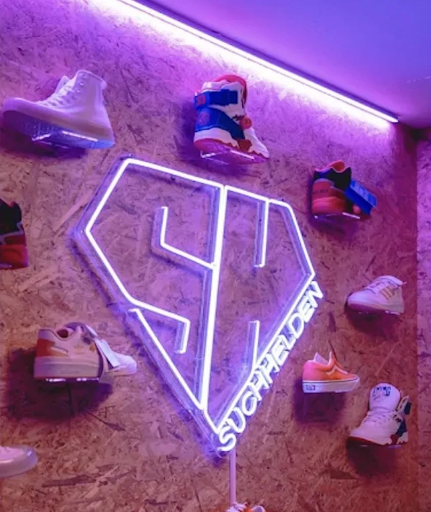 Leuchtendes Suchhelden-Neonlogo an der Sneaker-Wand im Büro in Osnabrück